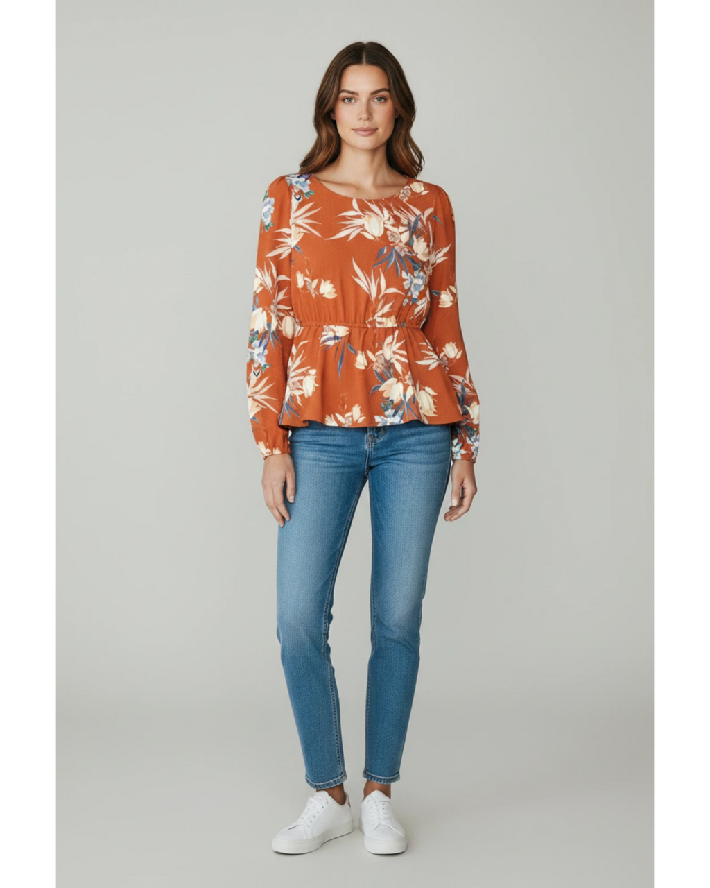 Modella indossa maglia ULTIMATAGLIA.COM arancio bruciato con stampa floreale, maniche lunghe e vita peplum elasticizzata