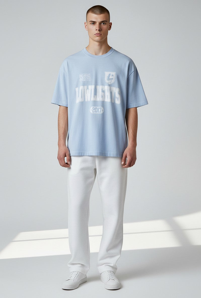 Modello indossa T-shirt oversize azzurra ULTIMATAGLIA.COM in cotone pesante con stampa grafica varsity bianca