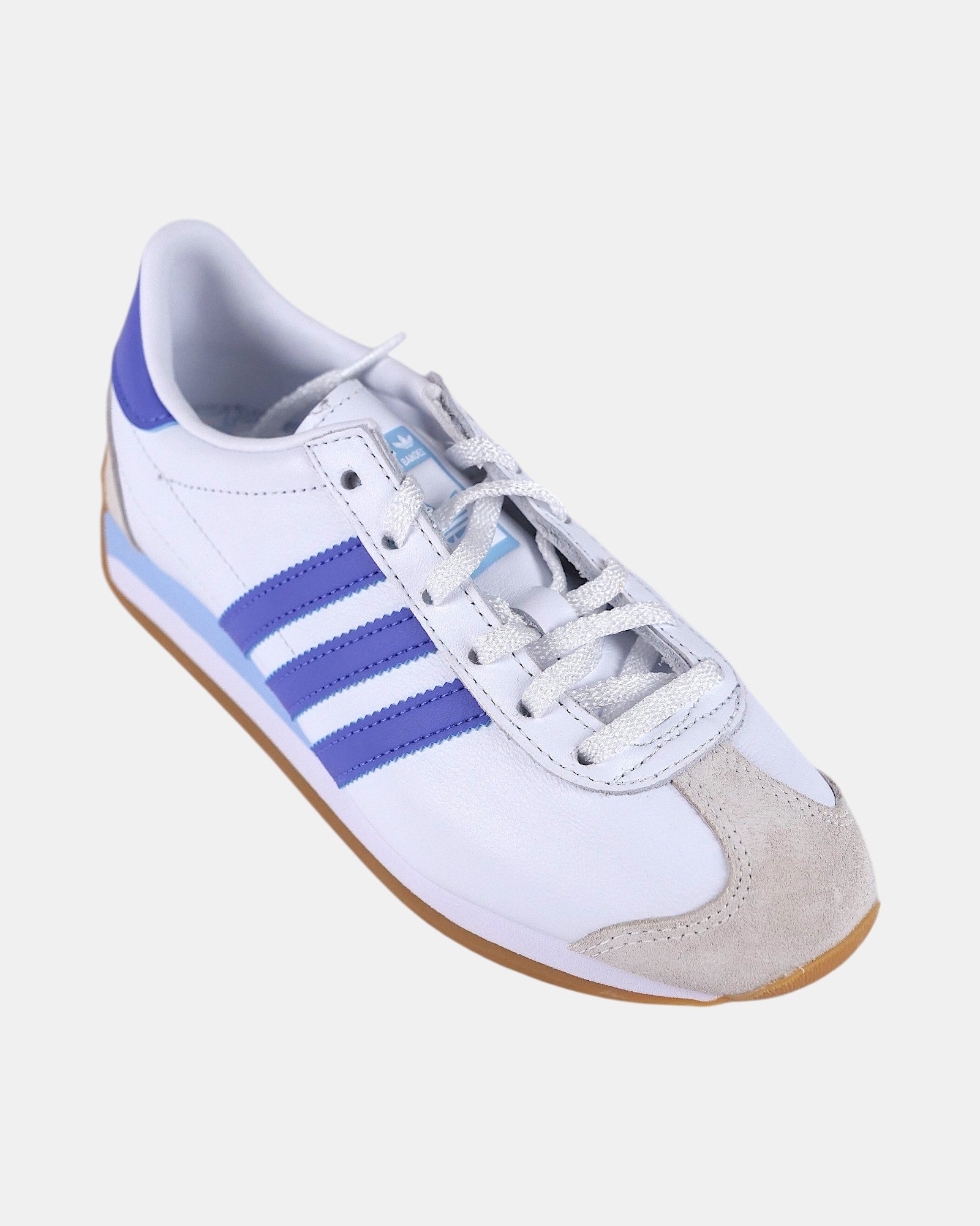 Sneakers Adidas Originals Country OG W bianche in pelle con strisce blu cobalto e suola gum. Dettagli scamosciati sul puntale.
