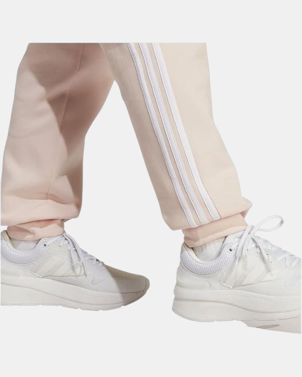 Pantaloni Adidas Sportswear beige in fleece con iconiche tre strisce bianche laterali e cordoncino in vita.