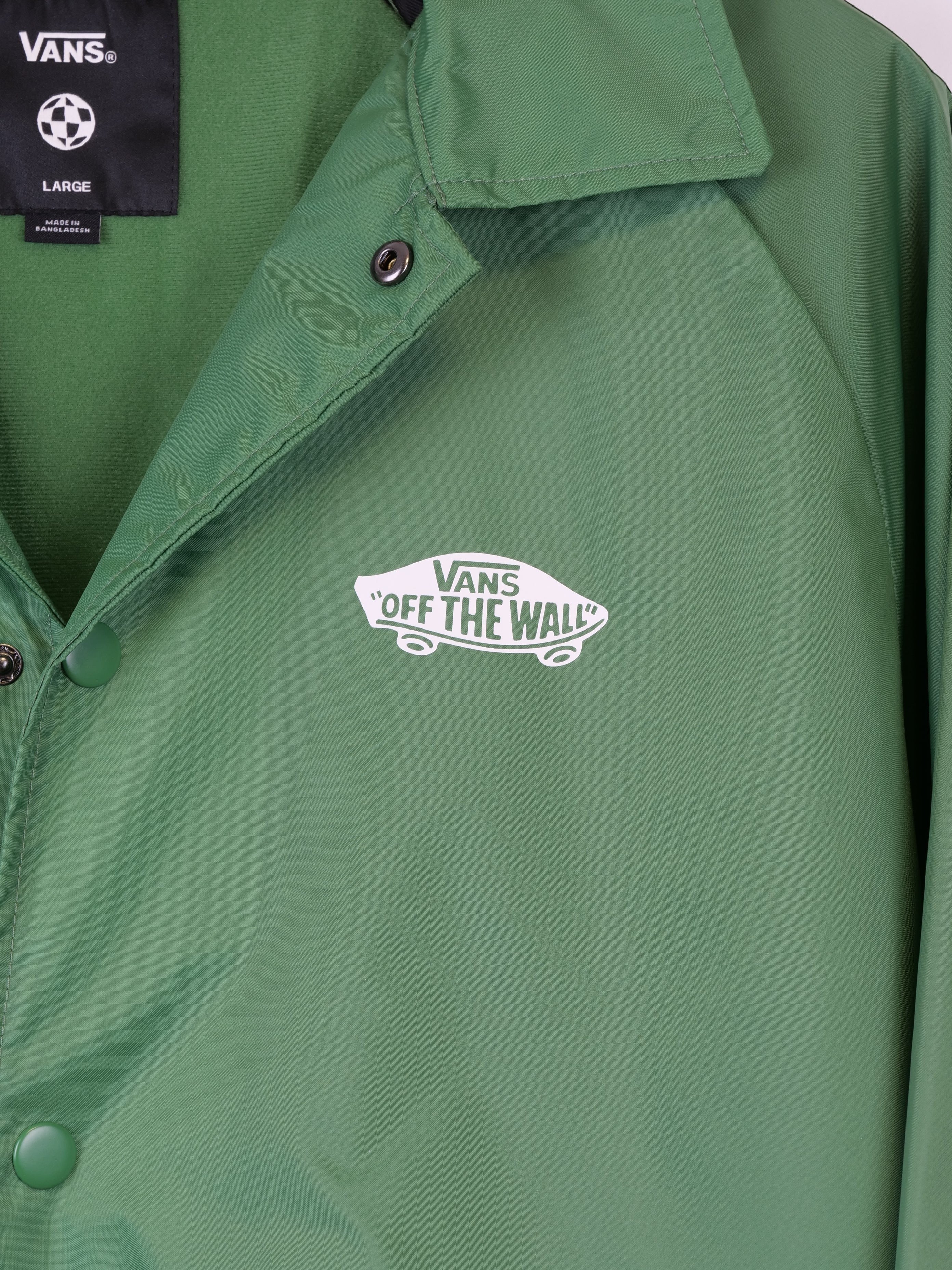 Giacca da uomo Vans verde in tessuto sintetico, modello Off The Wall Coach Jacket, con logo stampato sul petto e chiusura a bottoni.